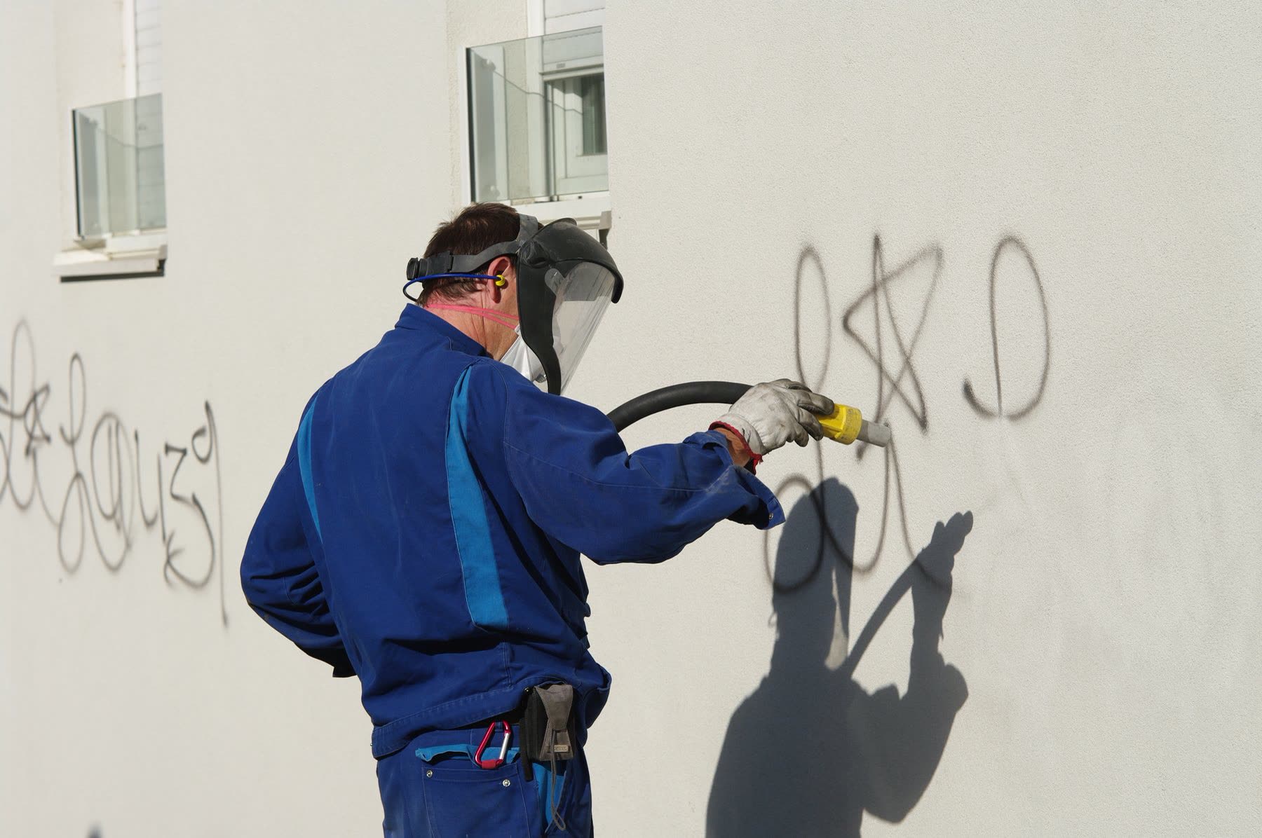 Profi entfernt Graffiti von Hausfassade mit Feinstrahltechnik